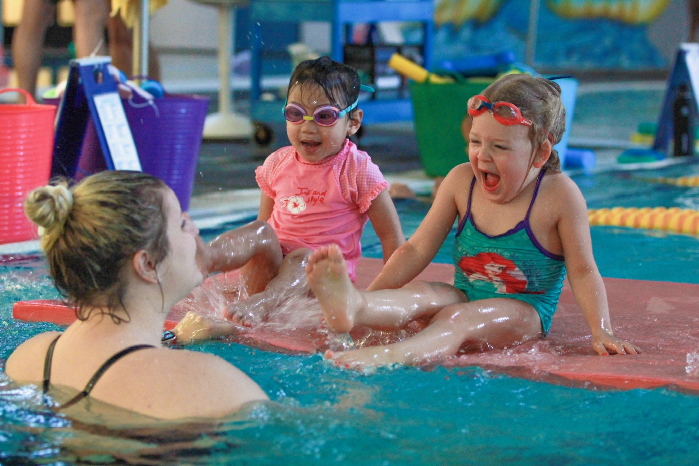 Students having fun learning to swim from energetic swim instructor