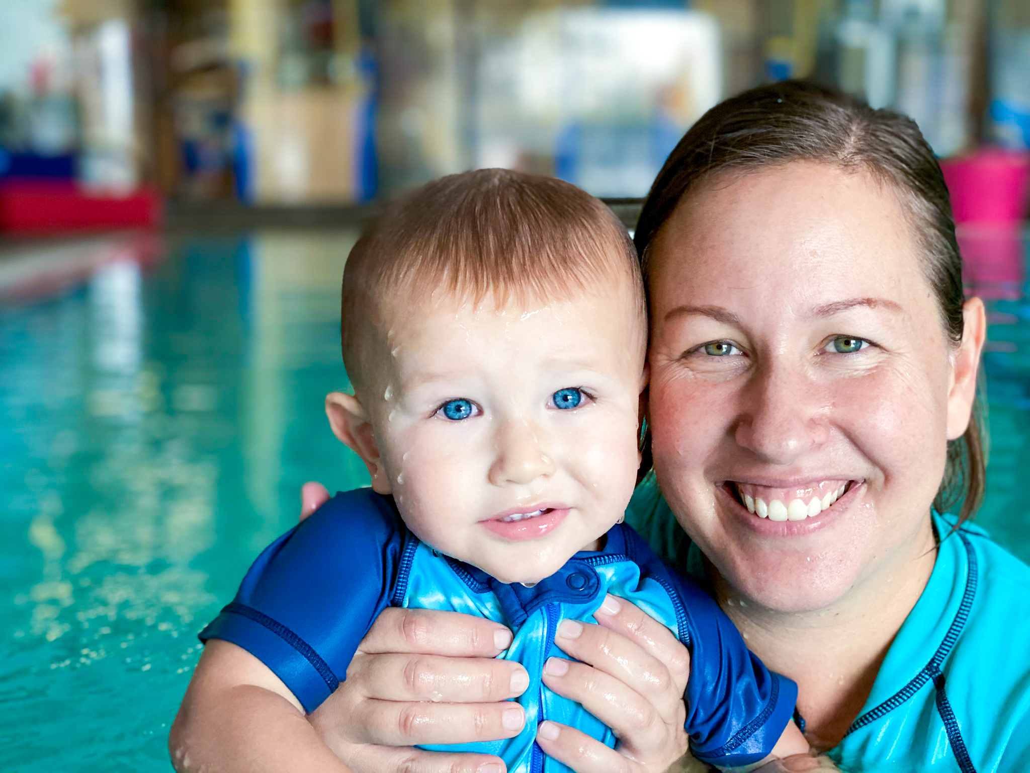 Mother teaches son to dive to the bottom of the pool for rings during parent child swim class