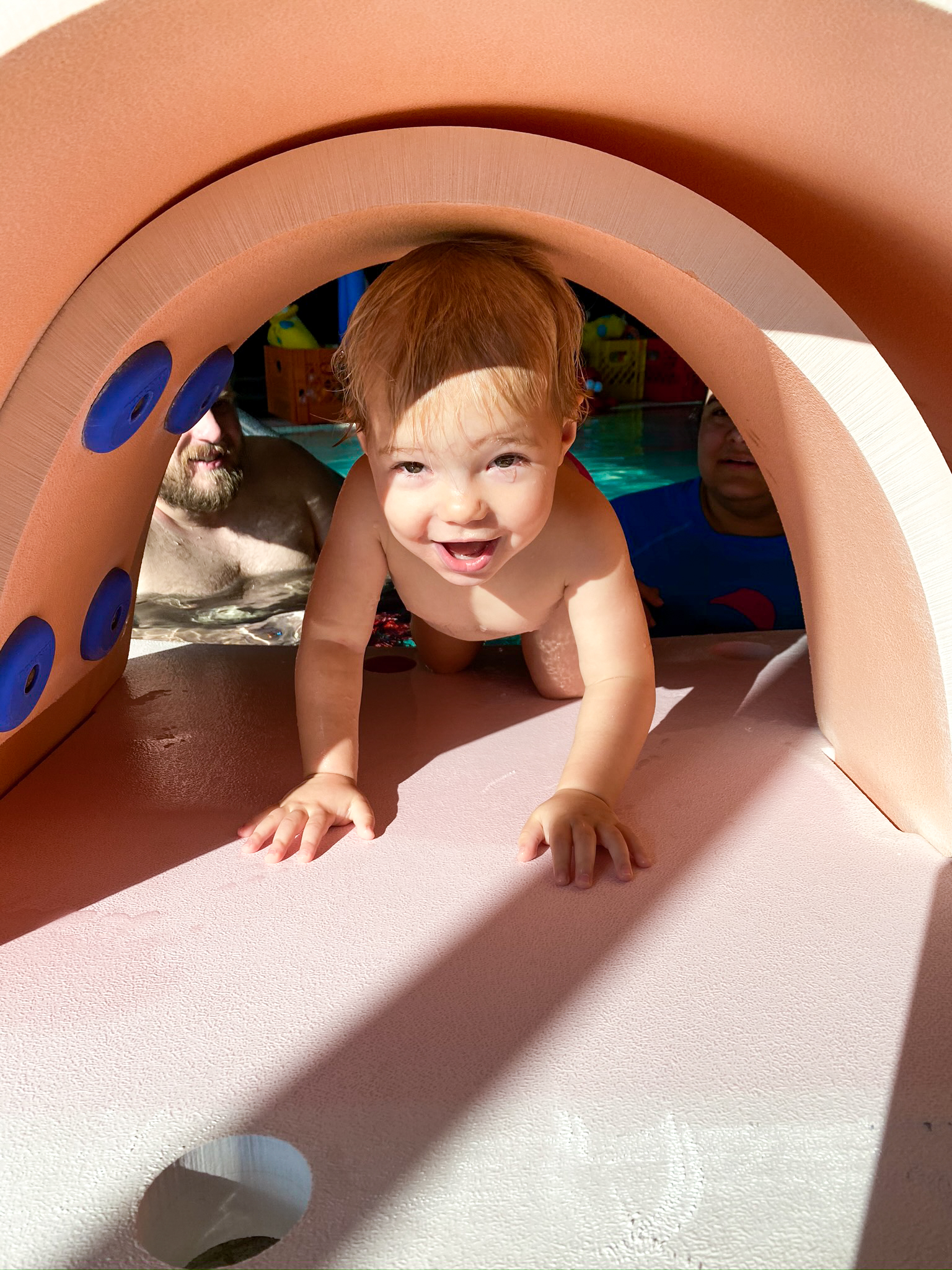 Baby loves explores swim tools and toys during parent child swim class