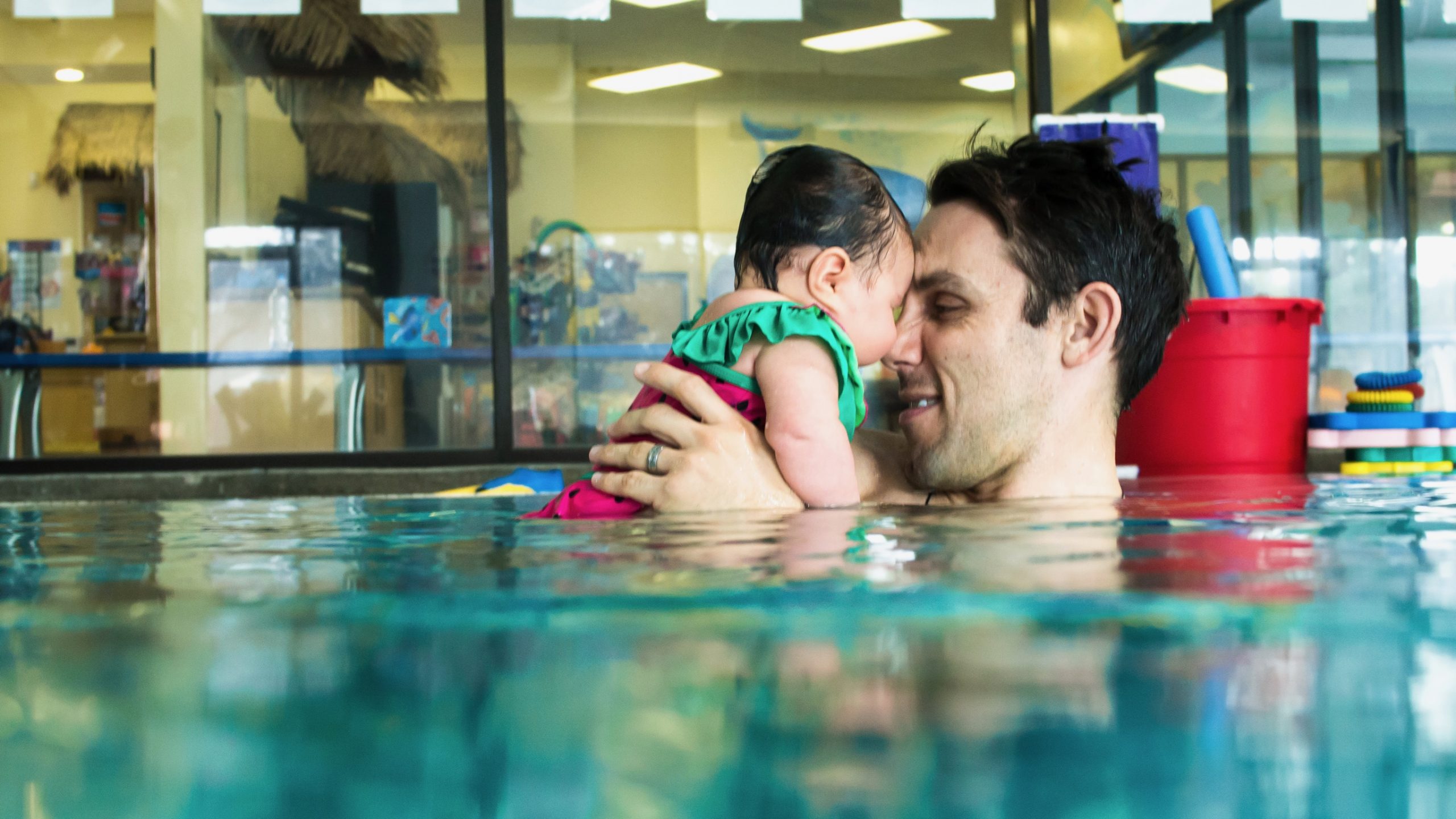 Father teaches infant daughter to swim in parent child swim class