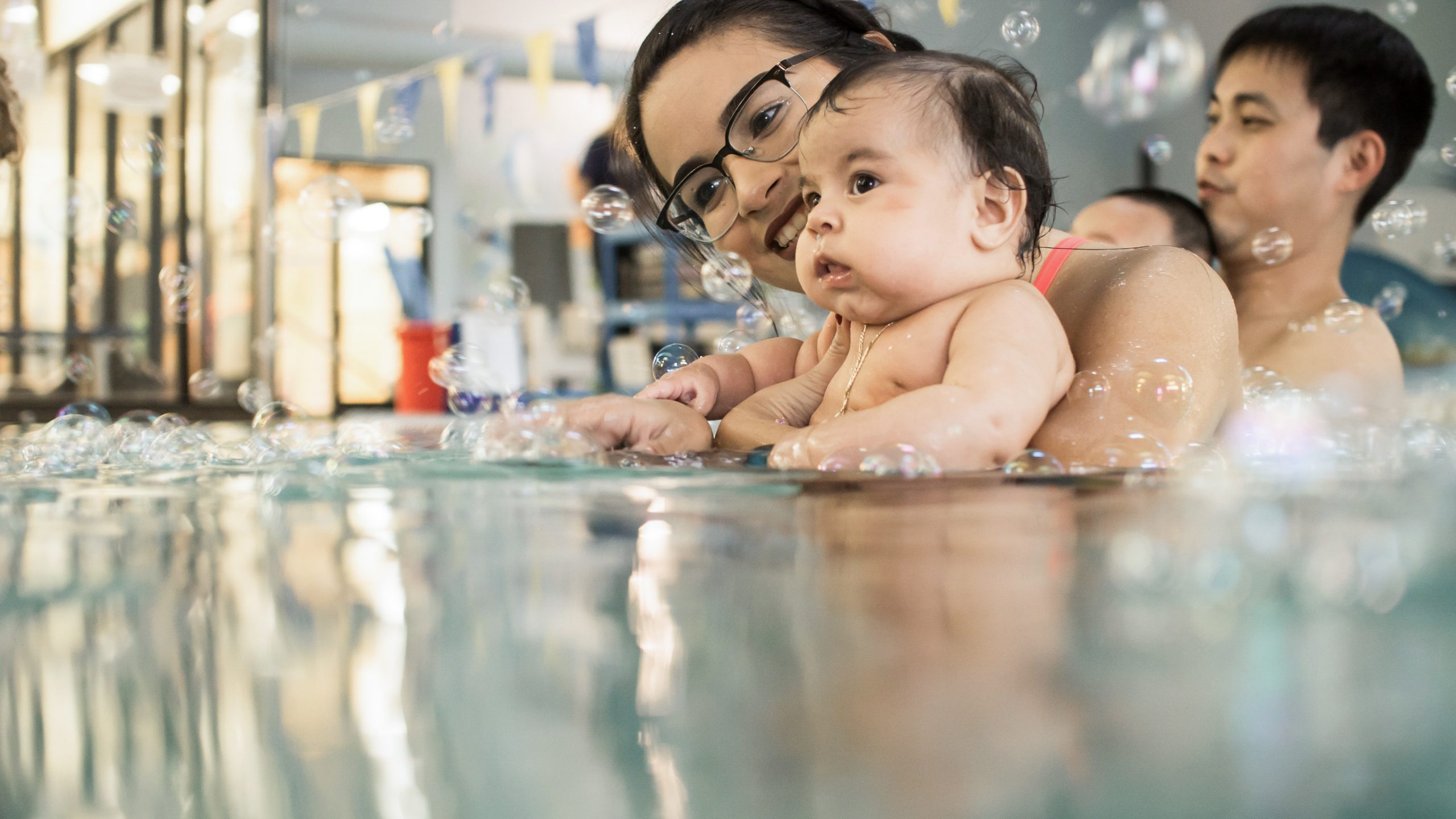 Mother and Infant playing with bubbles in parent child swim class