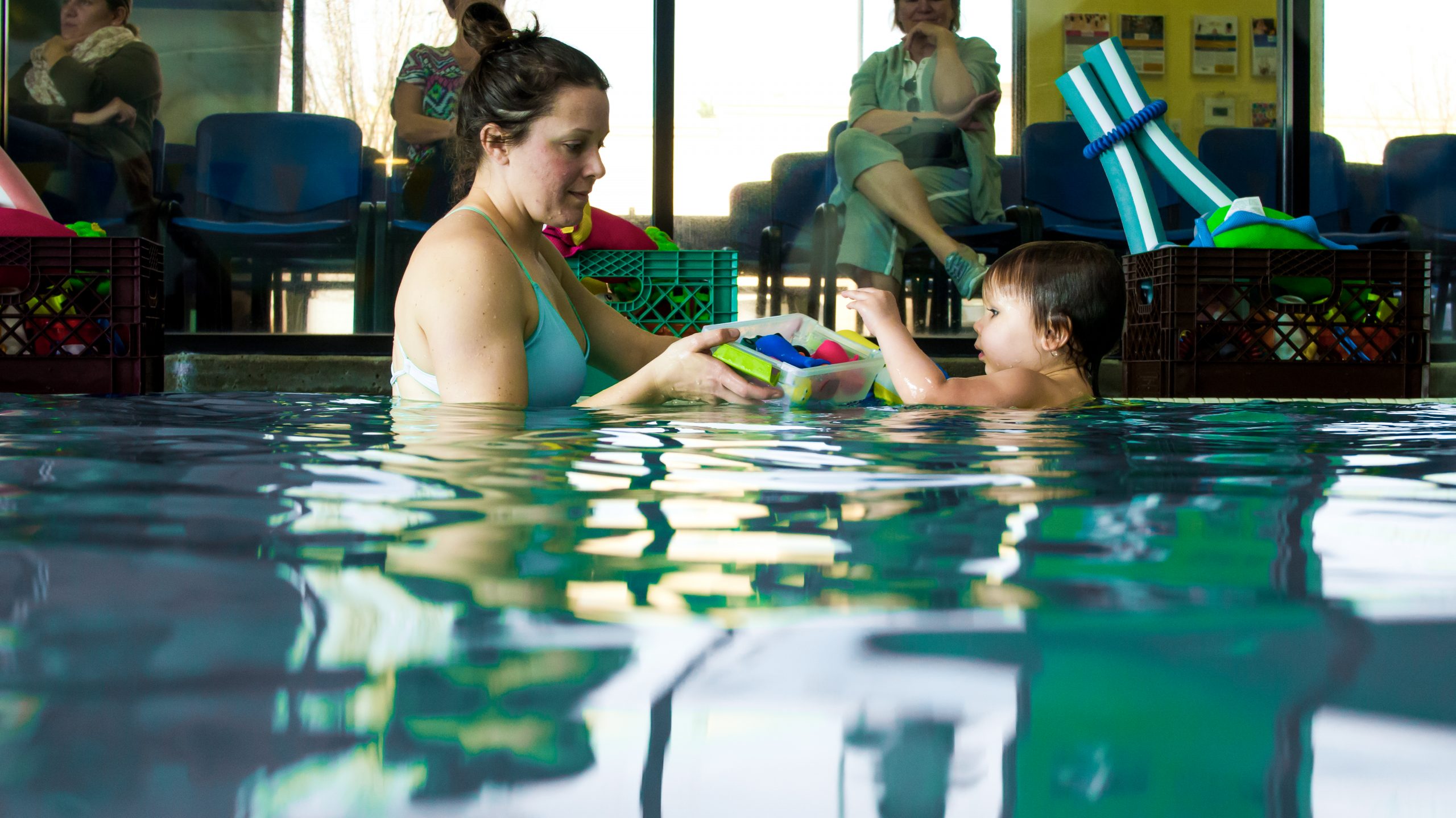 Mother teaches son to swim in an instructor lead parent child class