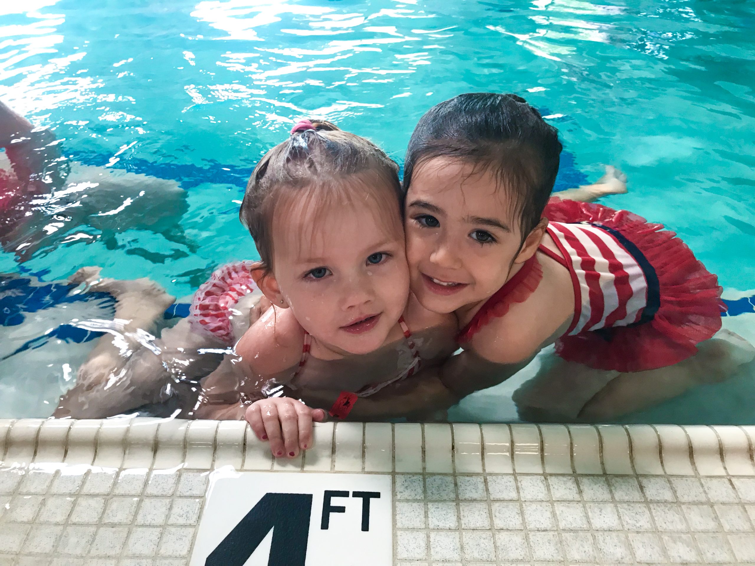 Swim lesson best friends hugging in pool