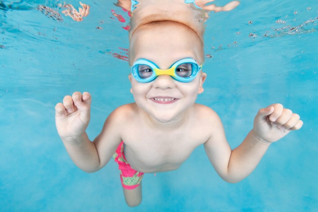 smiling boy swimming under water with goggles