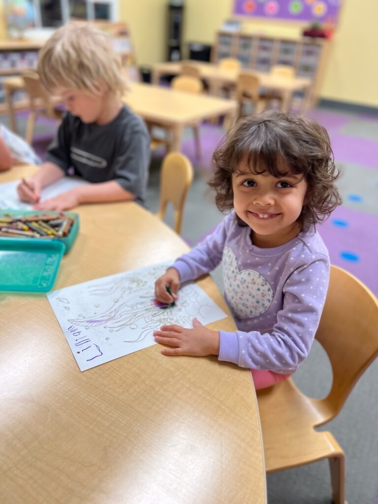 Young girl coloring image in preschool