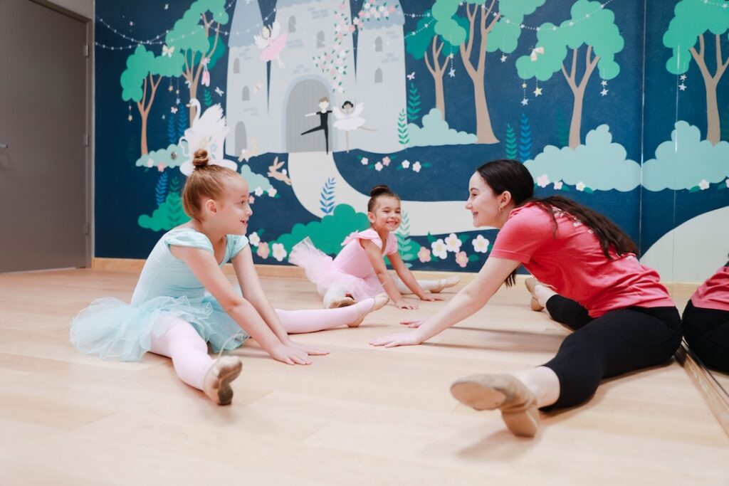Dance teacher and young students stretching in dance class