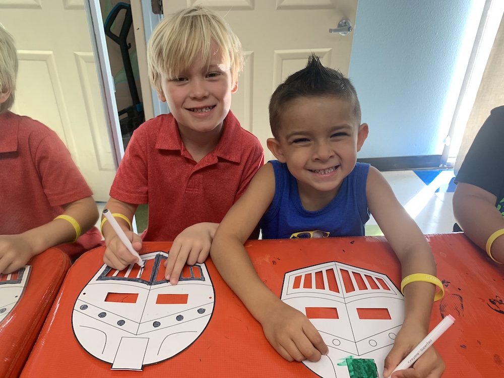 Two boys creating masks during summer camp at America's Kids In Motion.