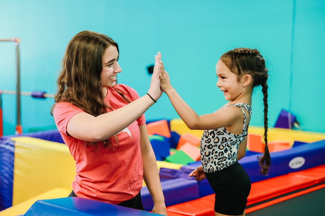AKIM teacher high-fiving a student in front of the foam block pit.