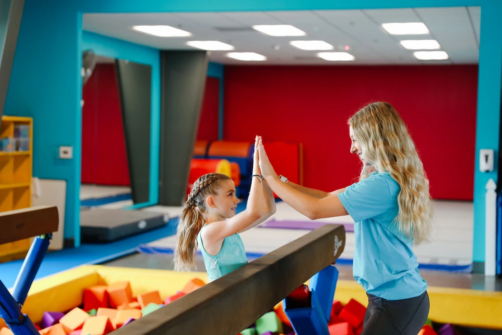 Gymnastics instructor working with a new student over a foam pit.